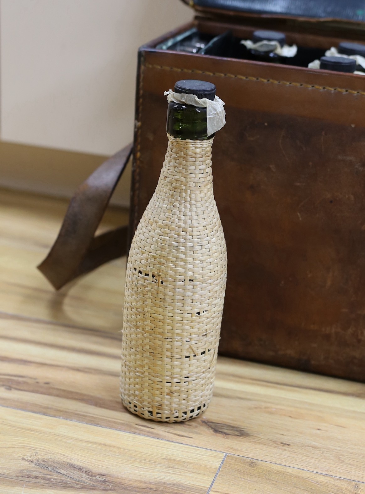 Automobilia related - an early leather cased car picnic hamper, with enamelled plates, basket work covered glass bottles and tumblers and plated cutlery